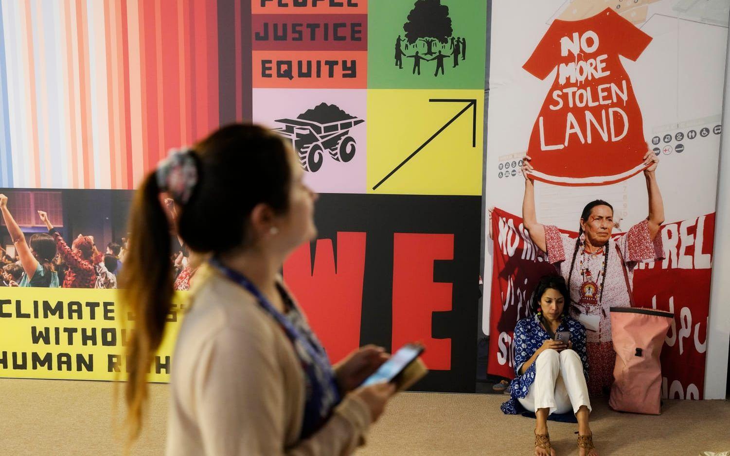 A person walks near a sign that reads "no more stolen land" at the COP28 U.N. Climate Summit, Thursday, Nov. 30, 2023, in Dubai, United Arab Emirates. (AP Photo/Rafiq Maqbool)  COP168